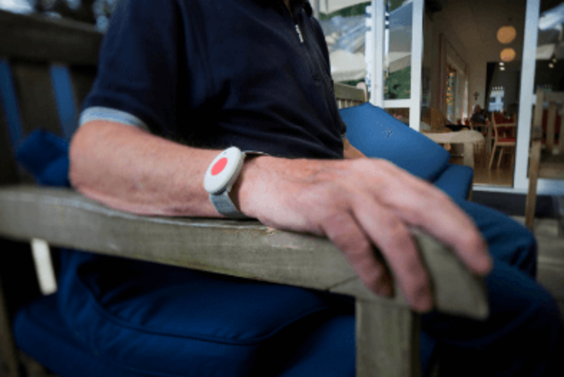 Eine Person sitzt auf einem Stuhl und trägt ein Hausnotruf Armband.
